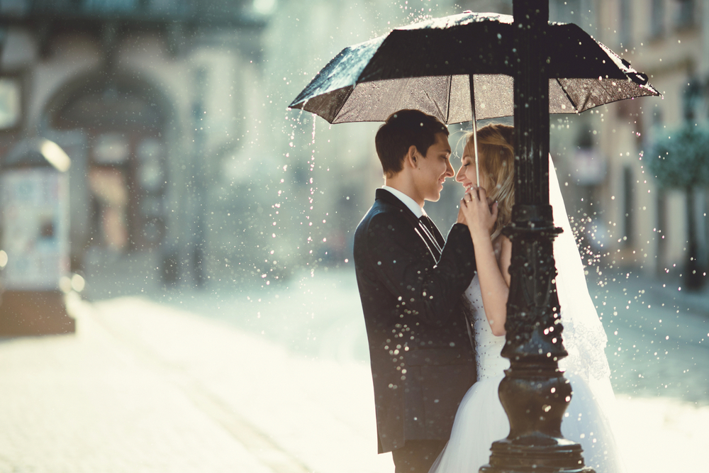Bride and Groom Standing Under an Umbrella. Howerton+Wooten Events.